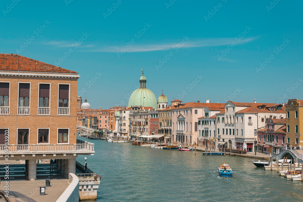 Grand canal in Venice, with big green dome in the distance on a sunny summer day