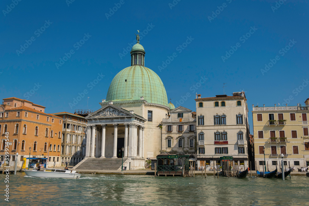 View of an ancient church, with huge green dome, in Venice, italy. view of a canal with historic buildings and boats