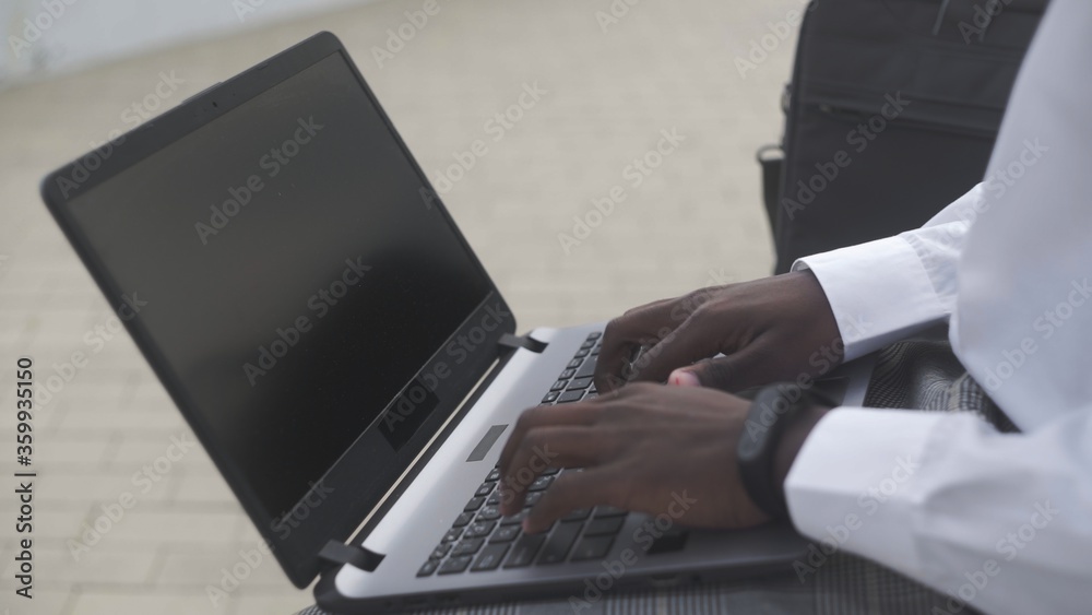 Close up of African American businessman working on laptop in park Close up of African American businessman working on laptop in park