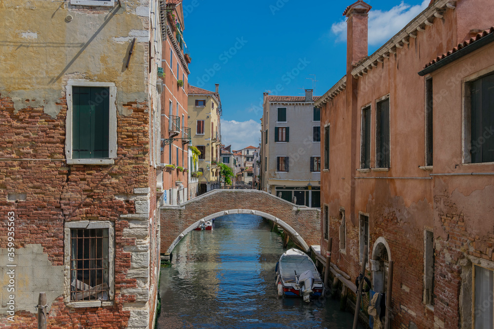 View of an old bridge over a small canal in Venice, Italy, with water and boat