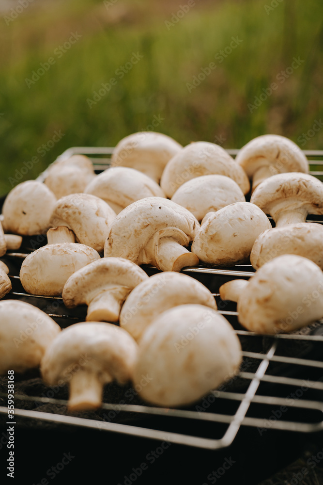 Cooking champignon mushrooms on the grill. Outdoor picnic. vegan food Cooking champignon mushrooms on the grill. Outdoor picnic. vegan food