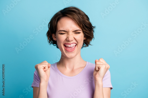 Portrait of delighted girl celebrate lottery fortune lucky win raise fists scream yeah wear good look mood clothes isolated over blue color background