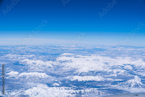 a landscape view from an airplane of snow-capped rocky mountains