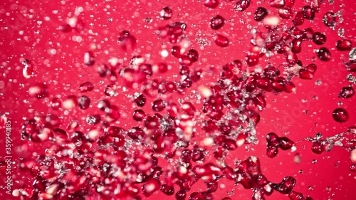 Super Slow Motion Shot of Fresh Pomegranate Seeds and Water Side Collision on Red Background at 1000fps. photo