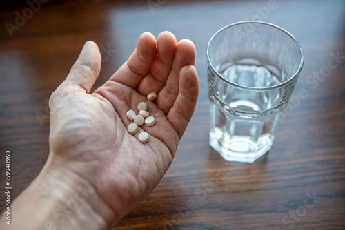healthy lifestyle, medicine, nutritional supplements and people concept - close up of male hands holding pills and water glass