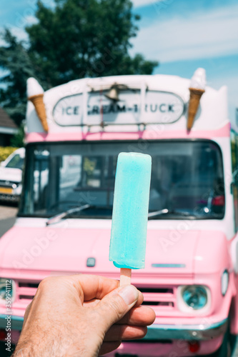 Pastel blue ice cream with a pink ice cream truck or van in the background. High quality photo. POV shot. Point of view.