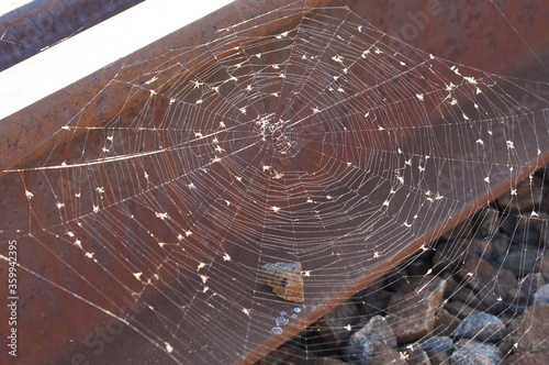a large web hangs on rusty metal rails