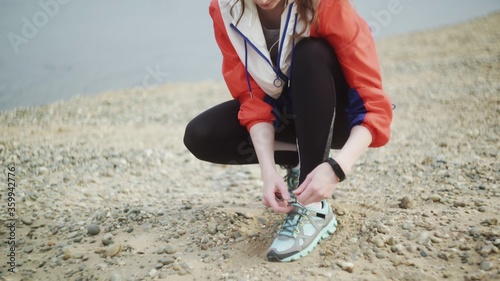 Young sporty female tying shoe lace and preparing to run