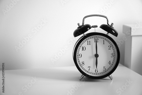 Wake up concept. Close up view of alarm-clock in morning bedroom environment. An image of a retro clock showing 06:00 am.