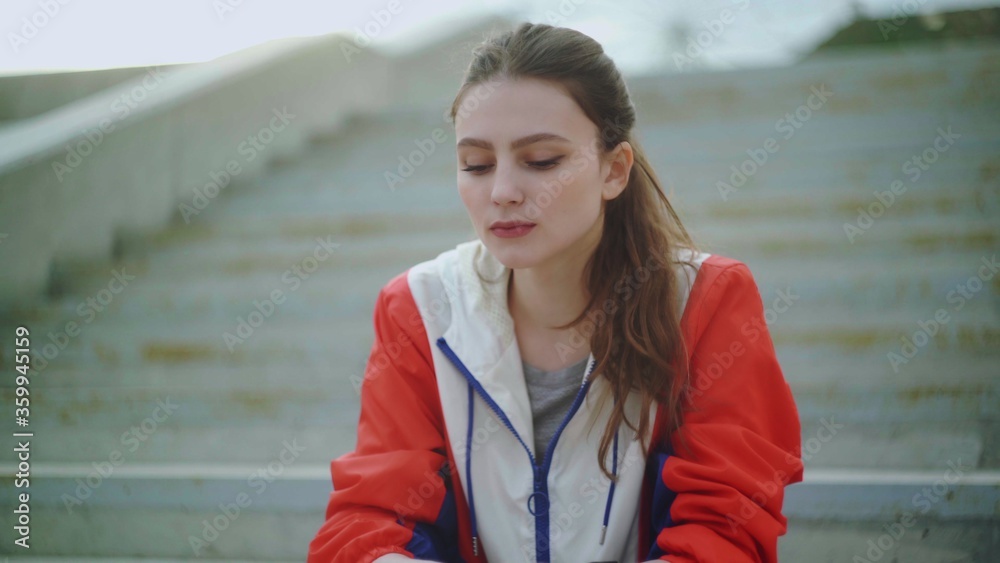 Attractive woman runner is sitting on stairs and resting exhausted after intense running workout training cardio athletic Attractive woman runner is sitting on stairs and resting exhausted after intense running workout training cardio athletic