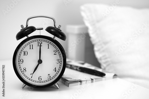 Alarm clock on table with notebooks and pen. Wake up concept. An image of alarm clock showing 07:00 am. 