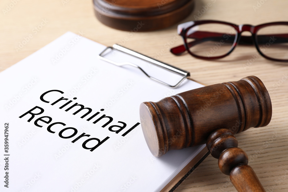 Clipboard with words CRIMINAL RECORD and gavel on wooden table, closeup Clipboard with words CRIMINAL RECORD and gavel on wooden table, closeup