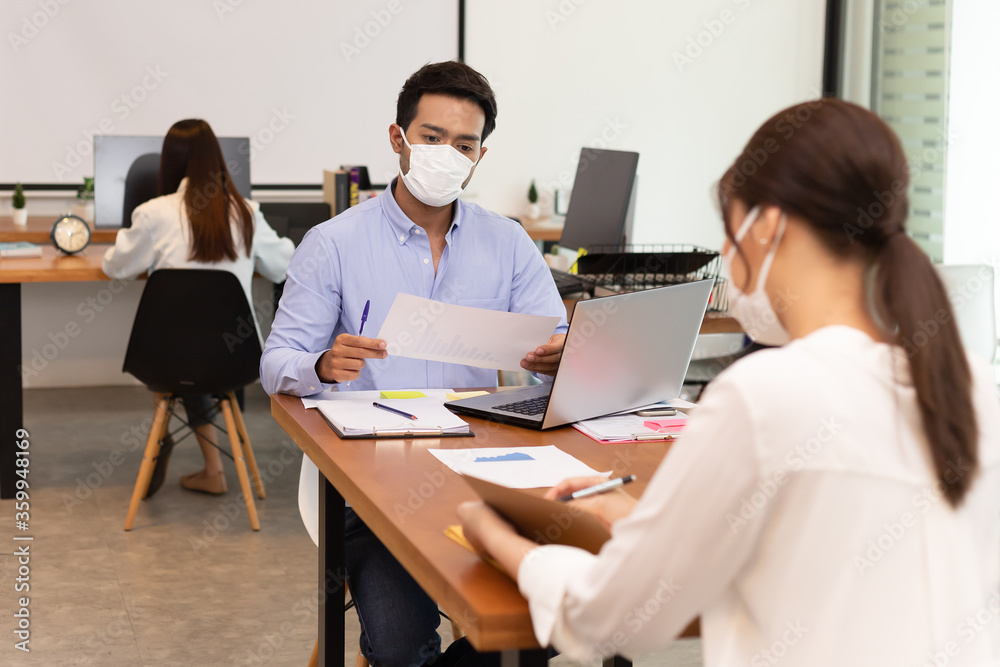 Obraz premium Asian business man and women talk about job and wear masks.New nomal