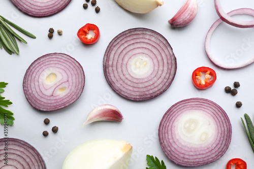 Flat lay composition with cut onion and spices on light background