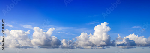 White fluffy yet majestic cumulus clouds on deep blue sky background, panoramic format © Smileus