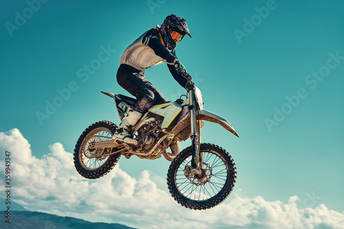 racer on mountain bike participates in motocross race, takes off and jumps on springboard, against the blue sky. Close-up. concept of extreme rest, sports racing.