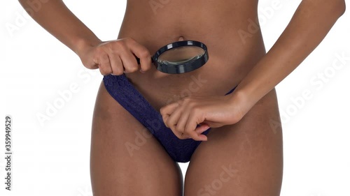 Close-up of a woman looking under her panties through the magnifying glass on white background photo