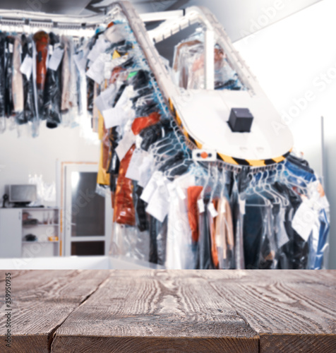 Empty wooden surface and blurred view of dry-cleaner's, space for text