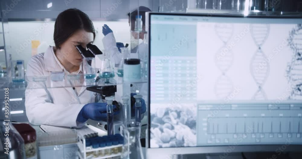 Female team working in modern laboratory. Studying genetic material with microscope. Using computer Female team working in modern laboratory. Studying genetic material with microscope. Using computer