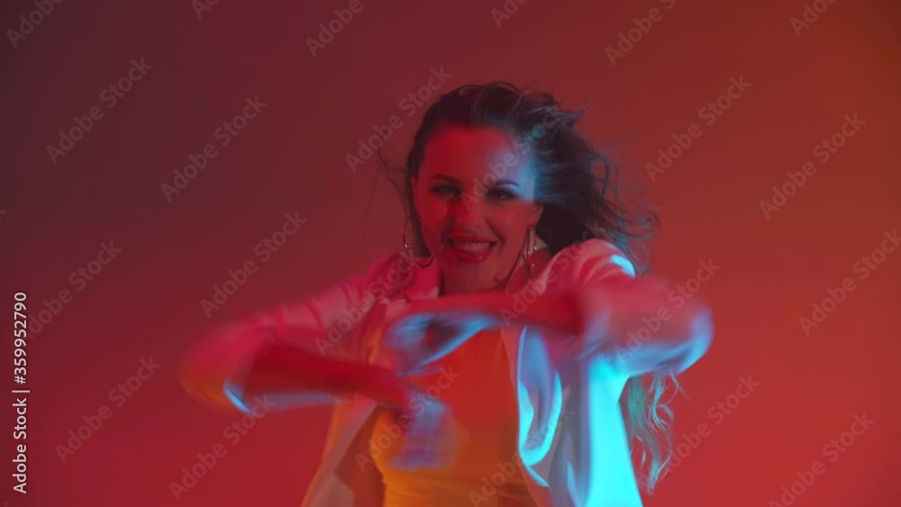 An incendiary young beautiful woman dances sings and looks at the camera in the light of spotlights colored neons and flashing lights An incendiary young beautiful woman dances sings and looks at the camera in the light of spotlights colored neons and flashing lights