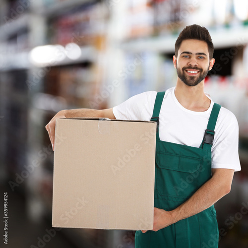 Принти на полотні Man wearing uniform with cardboard box in store. Wholesale market