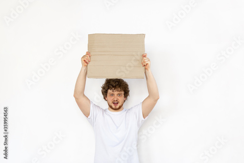 Young man protesting with blank board, sign isolated on white studio background. Activism, active social position, protest, actual problems. Meeting against human rights, abusing, freedom of choice.