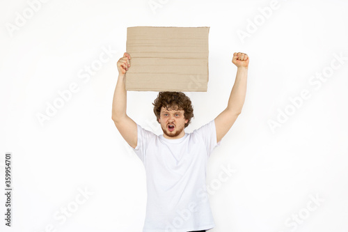 Young man protesting with blank board, sign isolated on white studio background. Activism, active social position, protest, actual problems. Meeting against human rights, abusing, freedom of choice.