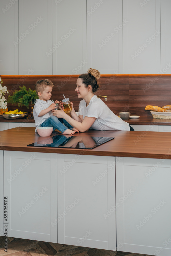 pregnant mother and son in the kitchen drink tea together
pregnant mother and son in the kitchen drink tea together