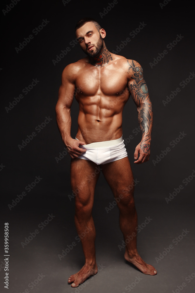 Sexy closeup portrait of handsome topless male model with beautiful eyes. Sexy man or muscular macho, bodybuilder, with muscle torso, body with six packs and abs poses on in white panties