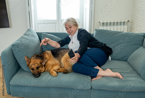 Senior woman with big dog talking on phone enjoying life at home. Stay home stay safe positive image