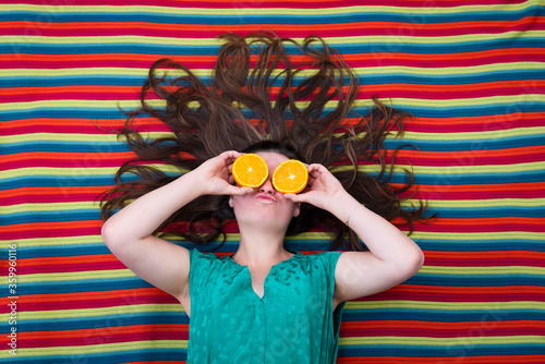 beautiful young girl holding oranges in front of the eyes  with a colorful background