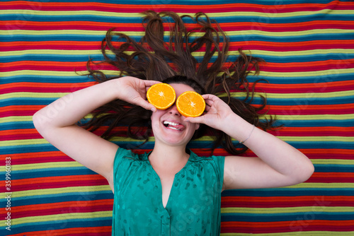 beautiful young girl holding oranges in front of the eyes  with a colorful background