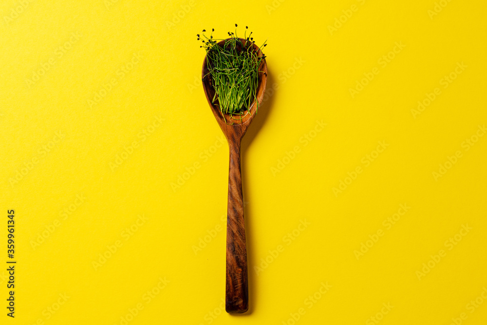 Micro greens in wooden spoon on paper background Micro greens in wooden spoon on paper background