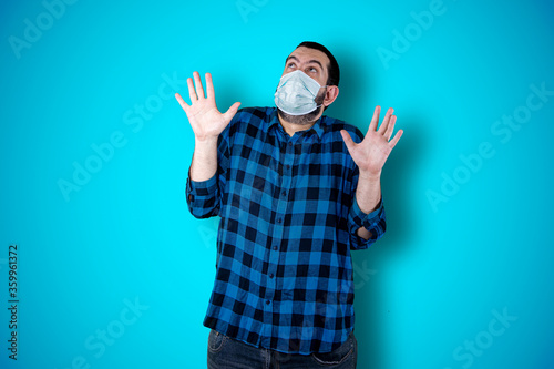 Man over isolated blue background studio with surprise facial expression. Coronavirus concept