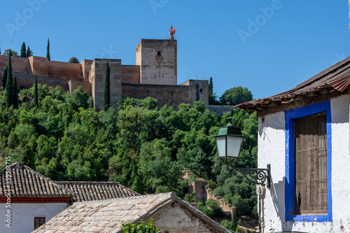 View of the Alcazaba of the Alhambra from the Albaicin with a blue-framed window in an old house