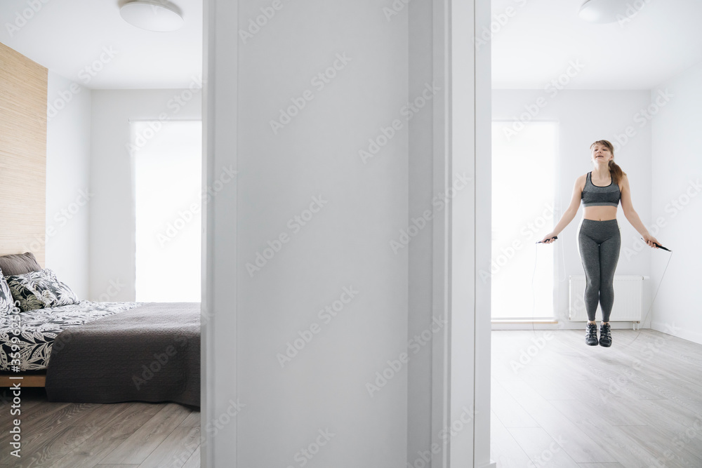 Woman during workout using jumping rope at home Woman during workout using jumping rope at home