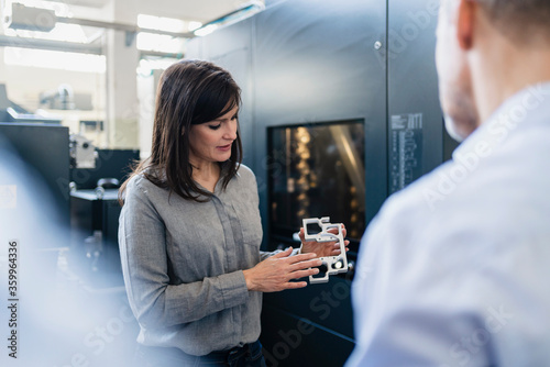 Businesswoman showing product to businessman in a factory photo