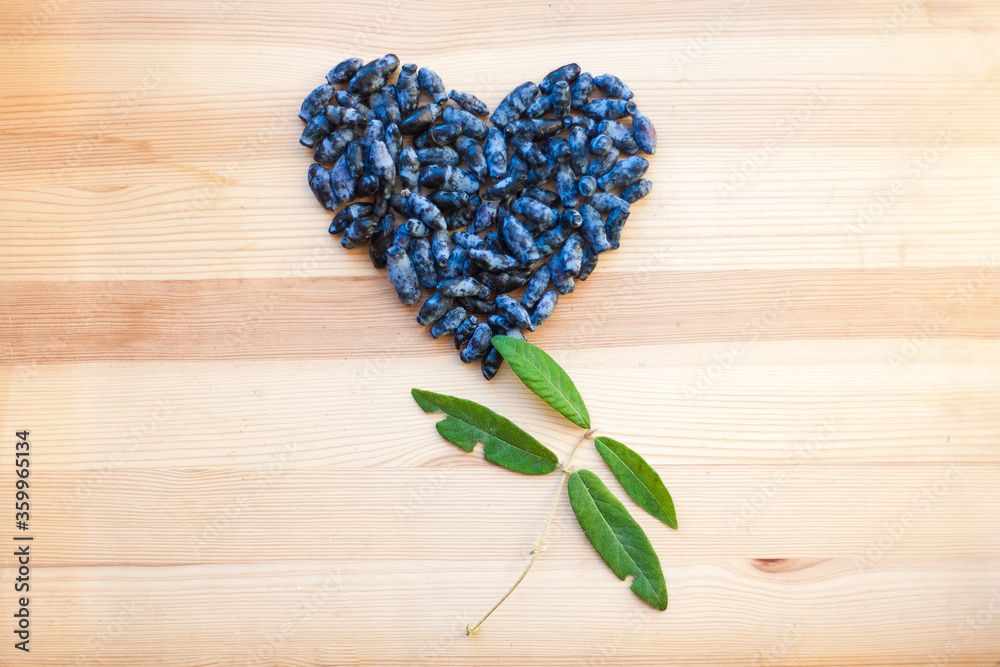 heart made from honeysuckle berries on wooden background. berries and honeysuckle leaves close-up heart made from honeysuckle berries on wooden background. berries and honeysuckle leaves close-up