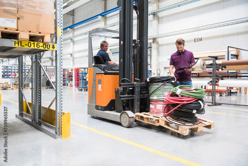 Warehouseman and worker on forklift in high rack warehouse Warehouseman and worker on forklift in high rack warehouse