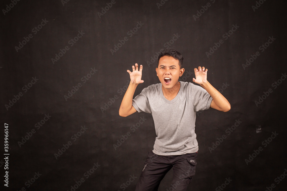 Angry and hate face of Young Asian man in gray shirt with angry hand gesture. Angry and hate face of Young Asian man in gray shirt with angry hand gesture.