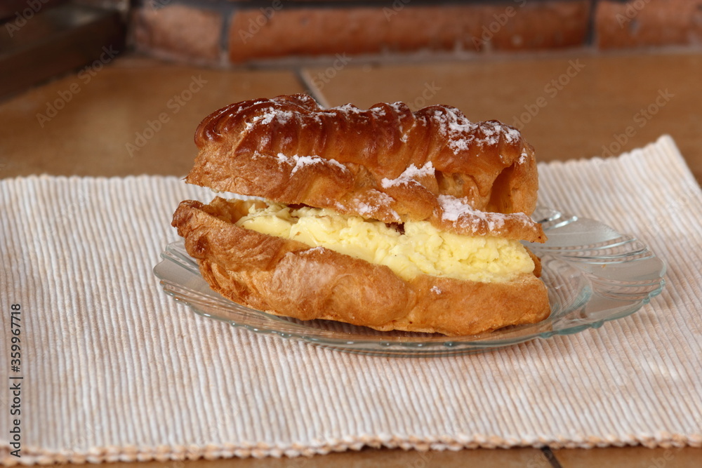 Eclair filled with pastry cream (custard) and topped with icing sugar Eclair filled with pastry cream (custard) and topped with icing sugar