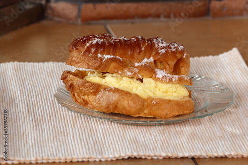 Eclair filled with pastry cream (custard) and topped with icing sugar