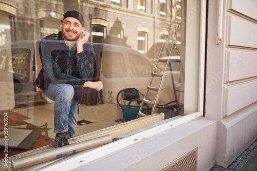 Man refurbishing shop location, using earphones at the window photo