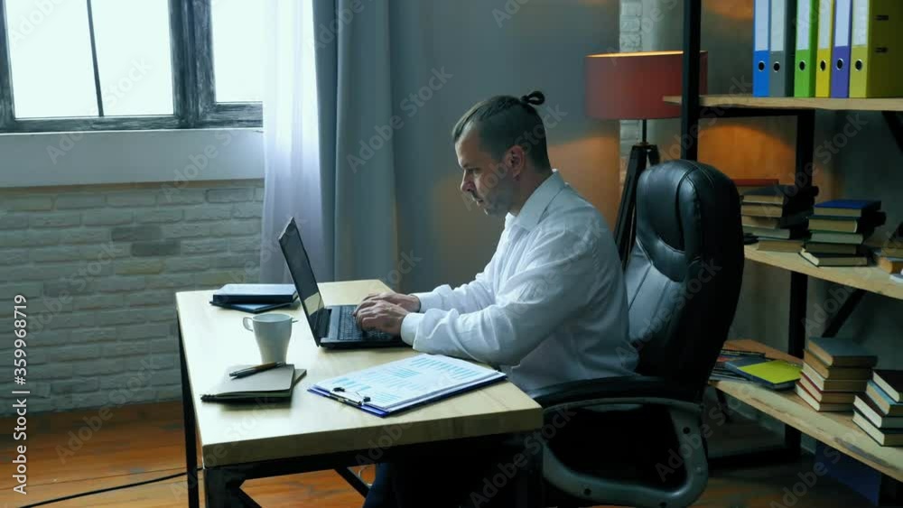 Focused man working with a laptop at a desk in the office. Focused man working with a laptop at a desk in the office.