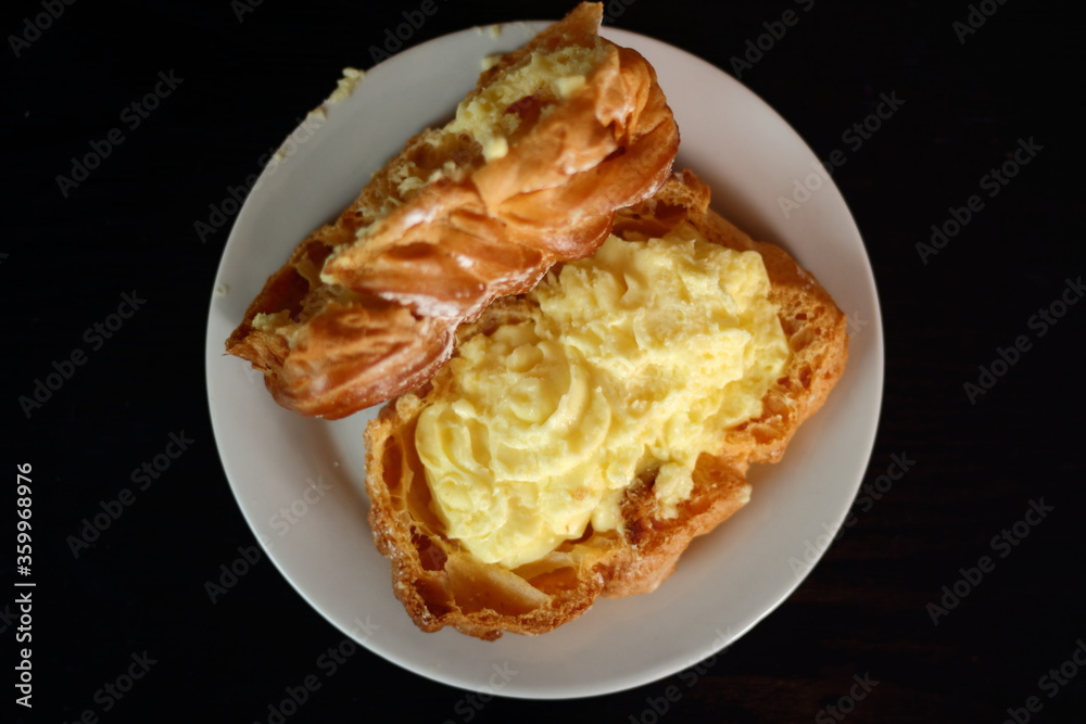 Fototapeta premium Eclair filled with pastry cream (custard) and topped with icing sugar