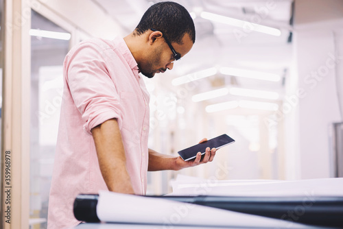 Afro american attractive architect dressed casual outfit watching training webinar for improving skills and knowledge on touchpad with 4G internet connection,young student engineer making coursework