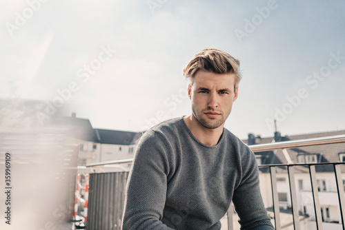 Portrait of cool young man sitting on balcony photo