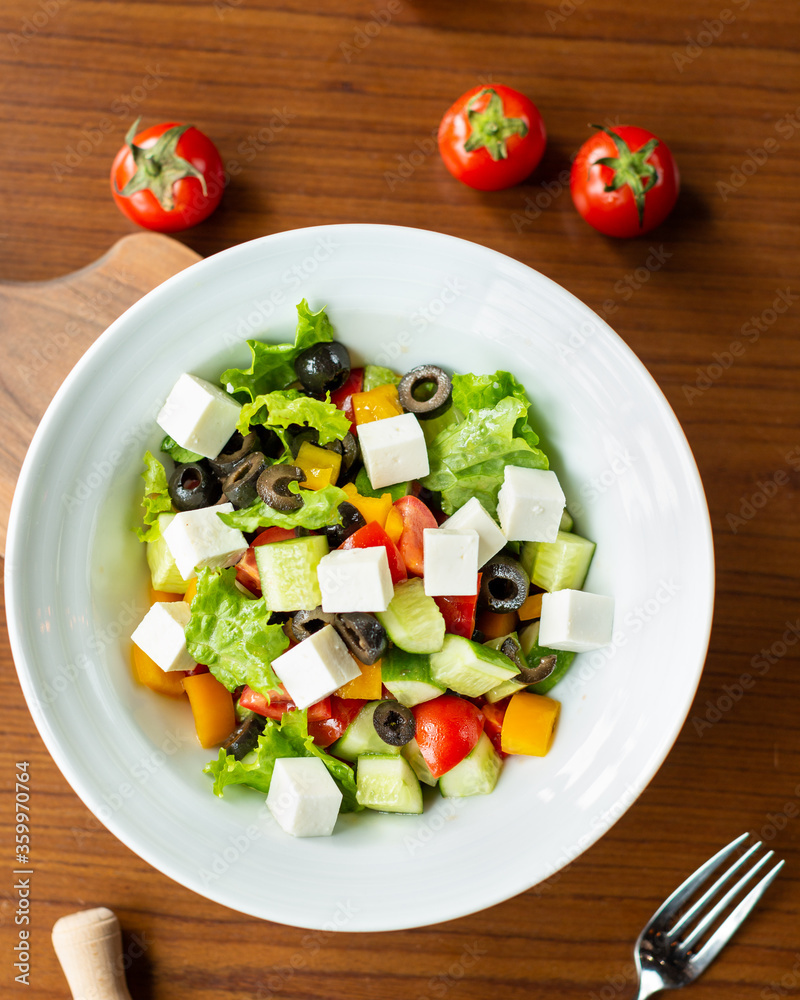 Greek salad in the white plate with tomatoes from top Greek salad in the white plate with tomatoes from top