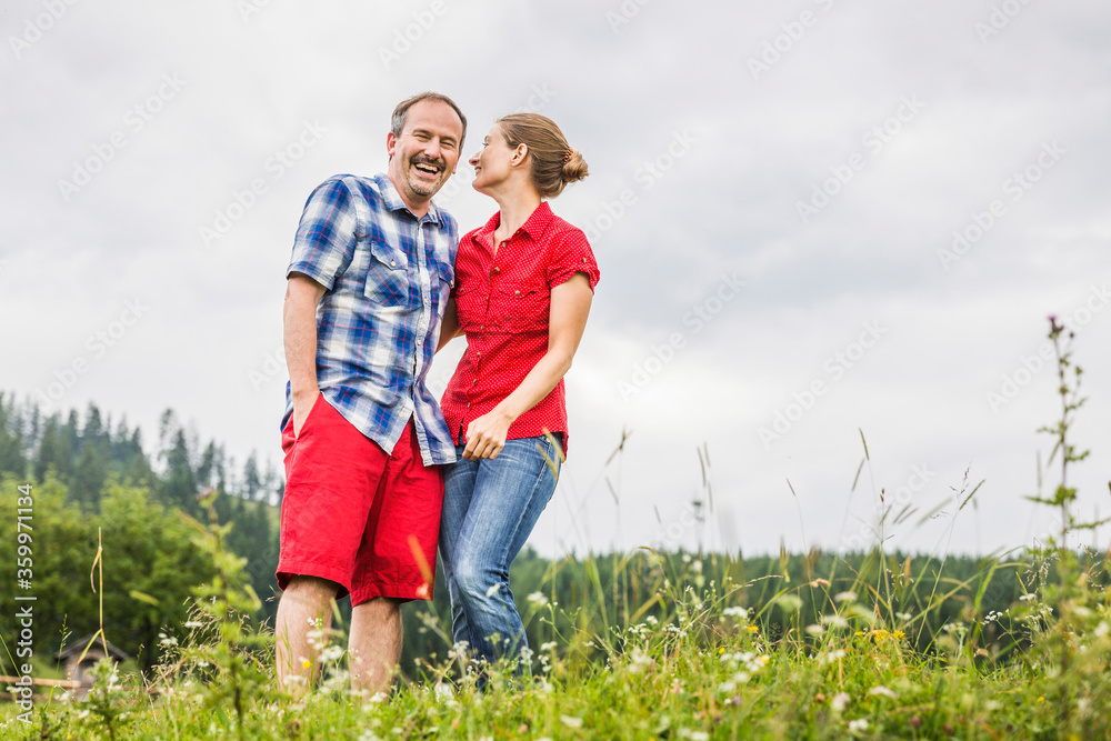 Happy couple standing on a meadow in the mountains, Achenkirch, Austria Happy couple standing on a meadow in the mountains, Achenkirch, Austria