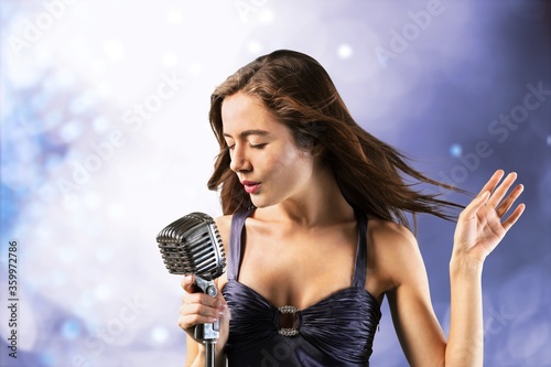Young beautiful woman singing with microphone